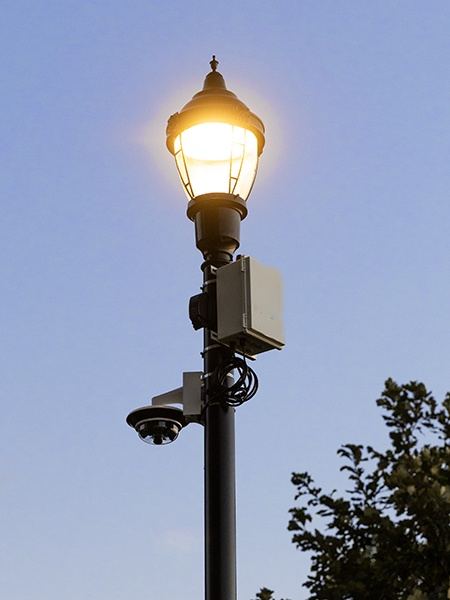 Power unit strapped to a decorative streetlamp pole with a multi-sensor camera below