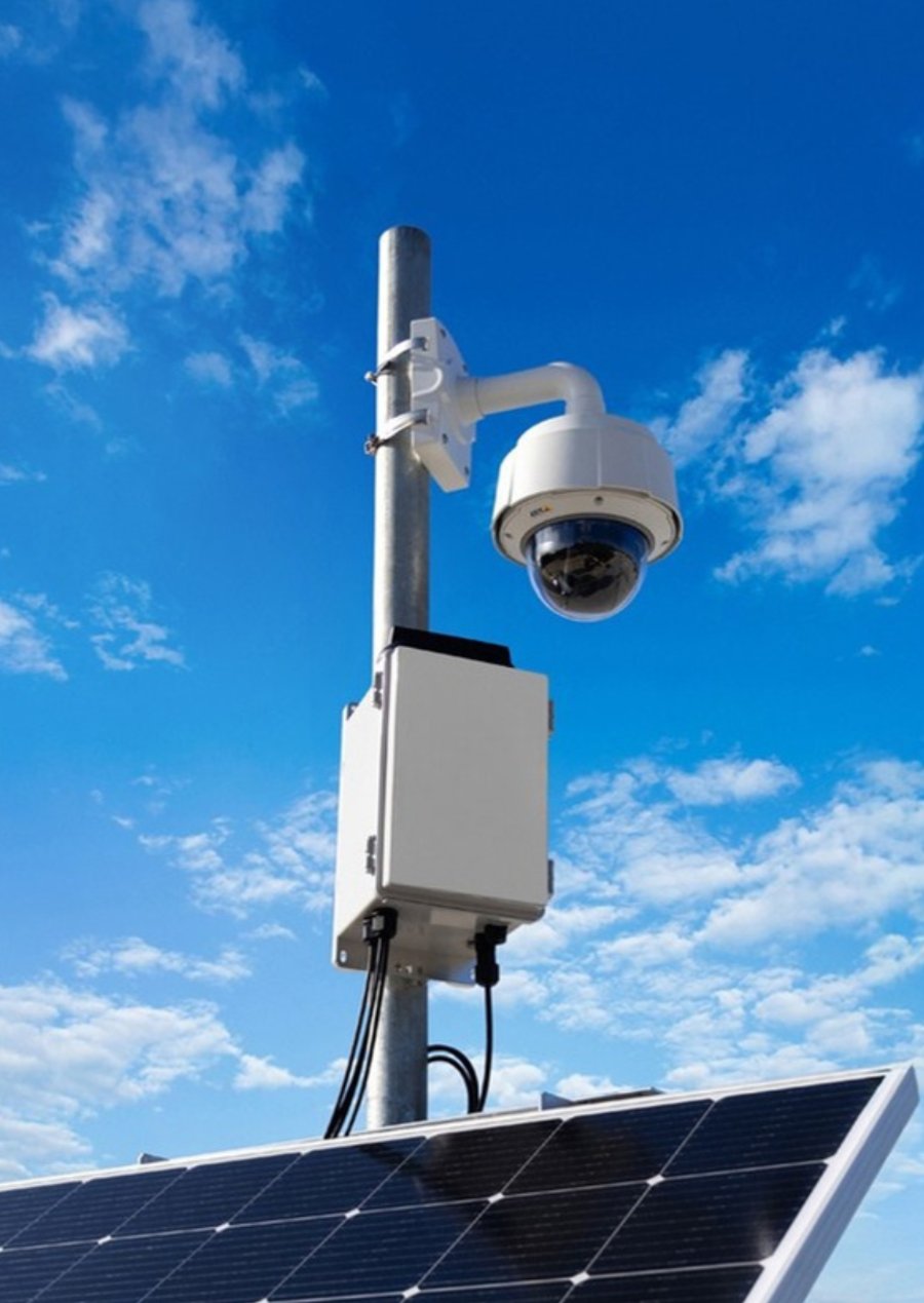 Dome camera, control cabinet, and solar panel mounted on a fixed pole against a blue sky
