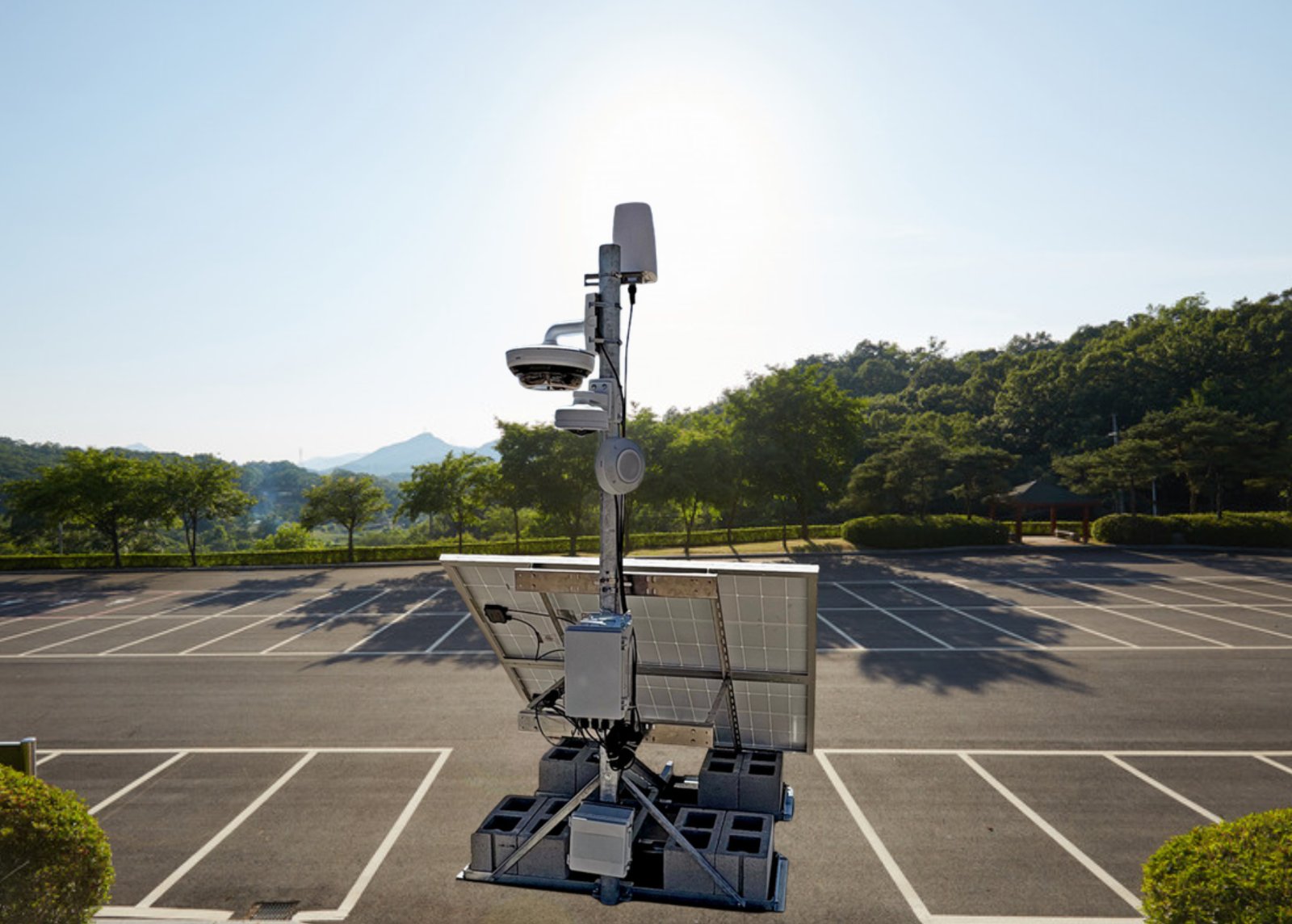 A portable surveillance mast with solar power standing in an open parking lot